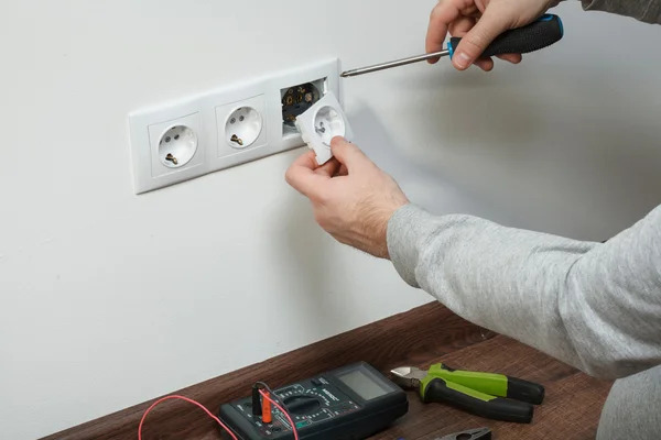 How to Plan Outlets and Switches for a Functional Room a-person-is-using-a-screwdriver-to-fix-or-install-a-ehite-triple-electrical-outlet-onto-a-wall