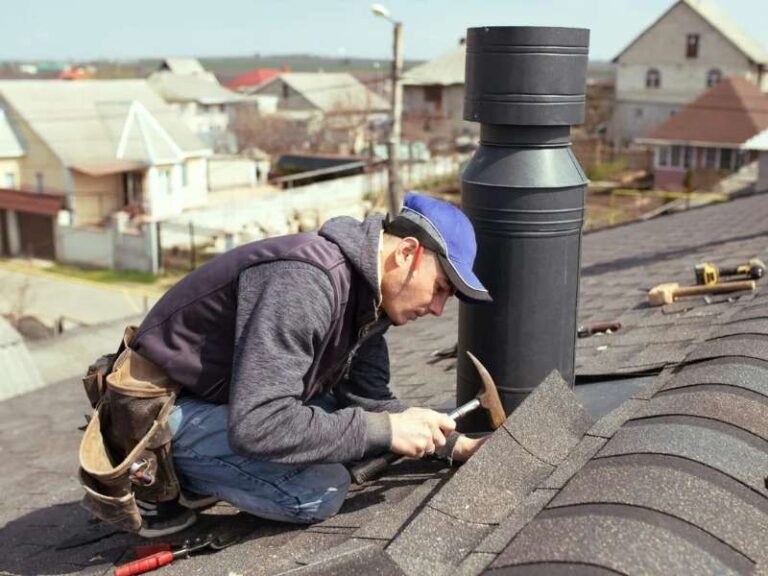 How to Know When Your Roof Needs More Than Repairs a-roofer-working-on-an-asphalt-shingle-roof-next-to-a-modern-black-modular-metal-chimney
