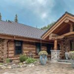 the-house-built-with-massive-dark-stained-horizontal-round-logs-it-features-multi-tiered-gable-roof-with-heavy-timber