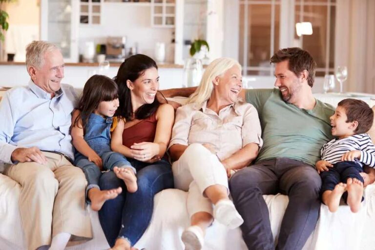 the-three-generations-a-grandparents-in-the-center-their-adult-children-and-their-two-young-kids-they-are-gathered-in-a-modern-living-room