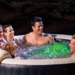 a-group-of-five-people-smiling-and-relaxing-inside-a-round-dark-grey-swimming-pool