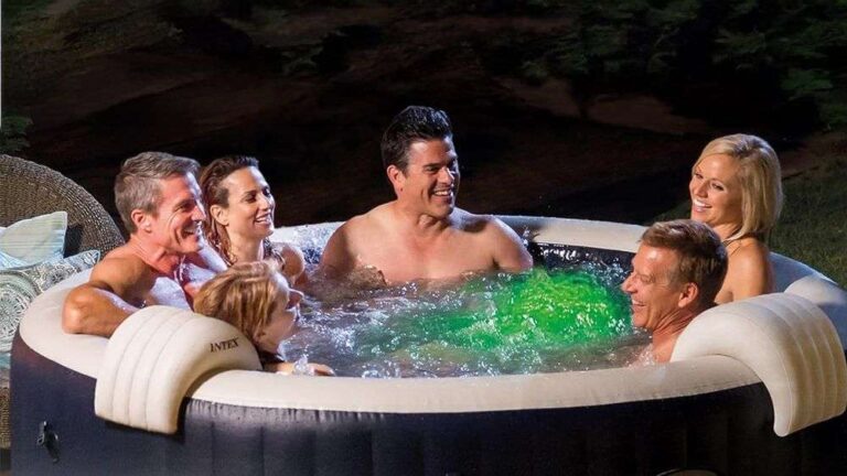 a-group-of-five-people-smiling-and-relaxing-inside-a-round-dark-grey-swimming-pool