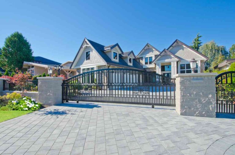 Top Design Ideas for 20 Ft Driveway Gates to Enhance Security and Curb Appeal a-large-black-wrought-iron-driveway-gate-featuring-a-prominent-arched-top-rail-the-gate-is-framed-by-two-substantial