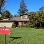 a-single-story-suburban-home-with-dark-grey-or-brown-roof-with-light-colored-siding-a-wide-green-lawn-covers-the-foreground