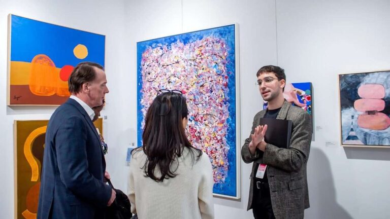 What Every First-Time Buyer Should Know Before Collecting Pop Art three-individuals-are-standing-inside-a-modern-well-lit-art-gallery-space-they-are-actively-gesturing-with-his-hands-as-explaining-a-art