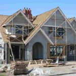 a-large-multi-story-residential-house-currently-under-construction-featuring-wooden-and-metal-scaffolding-surrounds-entire-front-of-the-building