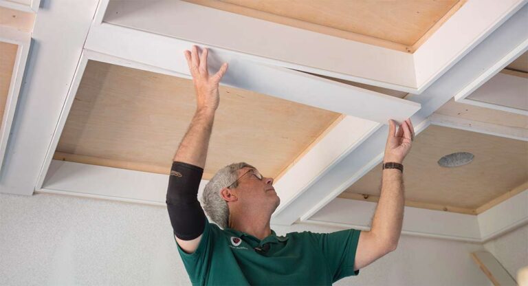 Dated Ceiling Looks (and What Designers Replace Them With) a-man-is-reaching-upward-toward-a-wooden-architectural-grid-overhead