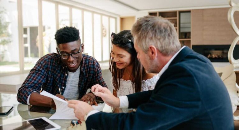 three-individuals-sitting-around-a-table-in-what-appears-to-be-an-office-setting-actively-reviewing-documents
